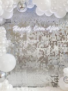 white and silver balloons are on display in front of a backdrop that says happily save the date