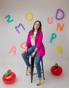 a woman sitting on a stool in front of letters