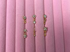 three pairs of gold and diamond earrings on pink velvet material, close - up photo