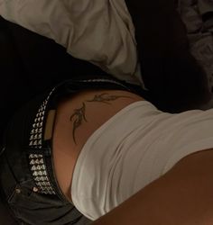 a woman laying on top of a bed with her stomach covered in black and white tattoos