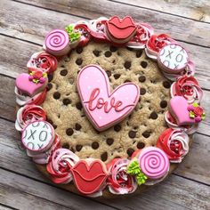 a cookie decorated to look like a heart with the word love spelled on it and lots of candies