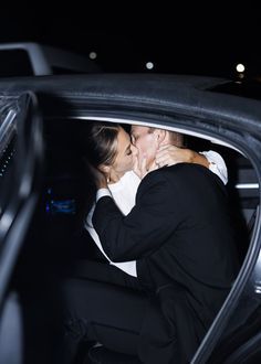 a man and woman are kissing in the back seat of a car at night time