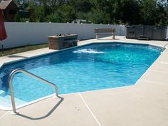 an empty swimming pool in the middle of a backyard with a grill and picnic table