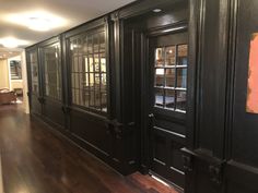 an empty room with wooden floors and black doors on either side of the room is a dining area