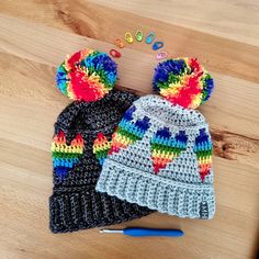 two crocheted hats sitting on top of a wooden table next to a marker