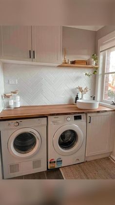 a washer and dryer in a small room with wooden counter tops on either side