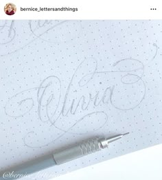 a pen sitting on top of a piece of paper next to a writing sample with the word virtura written in cursive