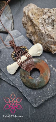 an assortment of jewelry items on display with rocks and stones in the background, along with a beaded necklace