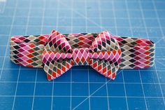 a close up of a bow tie on a cutting board with blue tiles behind it