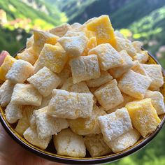 a bowl filled with sugar cubes on top of a green hillside covered in trees