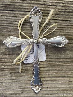 a silver cross with an ornate design on the front and sides, sitting on a wooden surface