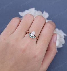 a person's hand holding a ring with a diamond and turquoise stones on it