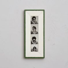 a white and green frame with four pictures hanging on it's side against a wall