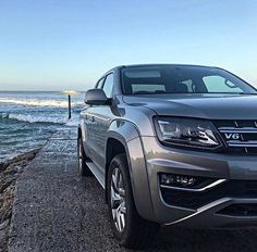 a silver truck parked next to the ocean