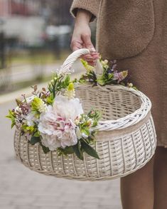 a person holding a basket with flowers in it