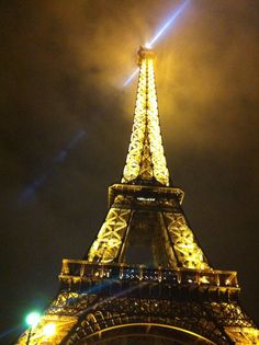 the eiffel tower lit up at night with lights on it's sides