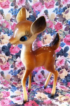 a small toy deer standing on top of a floral background