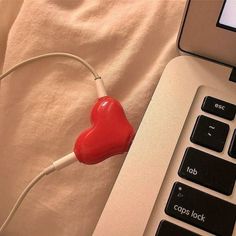 a red heart plugged in to a laptop computer with the keyboard on it's side