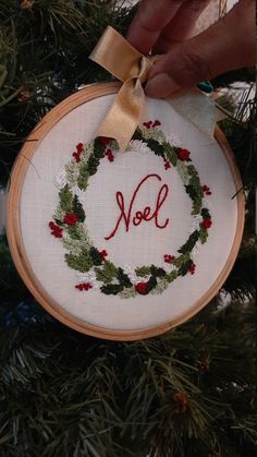 a hand embroidered ornament hanging from a christmas tree with the word noel on it