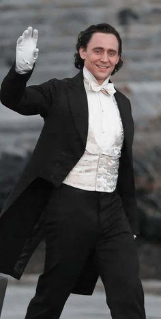 a man in a tuxedo waves to the crowd