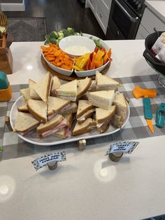 a plate full of sandwiches and carrots on a kitchen counter with other food items