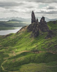 the mountains are covered in green grass and there is a body of water below them