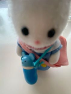 a small white teddy bear holding a blue toy elephant