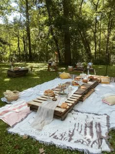 an outdoor picnic is set up on the grass with food and drinks laid out on it