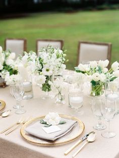 the table is set with silverware and white flowers