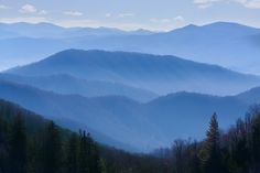 the mountains are covered in blue haze as seen from an overlook point on a sunny day