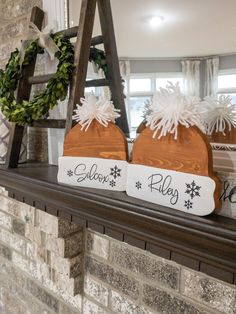 two wooden signs sitting on top of a fireplace mantel covered in snowflakes