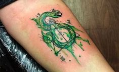 a green snake tattoo on the right arm and lower arm, with an hour mark in the middle