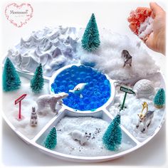 a snow globe with animals and trees in the middle, on top of white snow