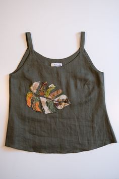 a green top with an embroidered leaf on it