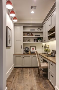 a home office with built - in cabinets and wooden flooring, along with an l shaped desk