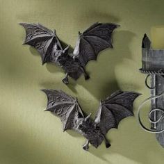 two bats are hanging on the wall next to a candle and some candlesticks