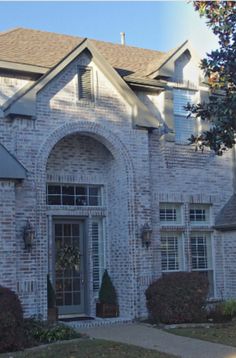 a brick house with white trim and arched windows