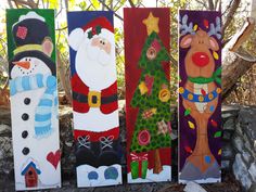 four painted wooden boards with santa, snowman, and christmas tree designs on them