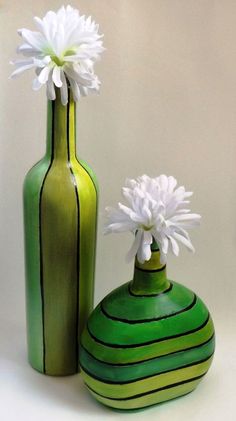 two green vases with white flowers in them