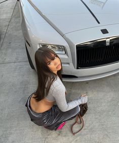 a woman sitting on the ground next to a car