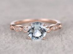 an oval aqua blue topazte and diamond ring with rose gold accents on the band