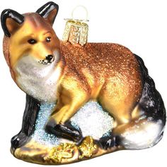 a glass ornament with a fox sitting on it's side and holding a christmas ornament in its mouth