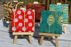 four small wooden easels with paintings on them