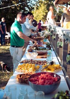 several people standing around a long table with food on it