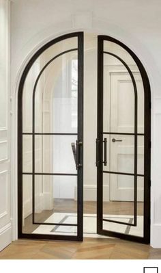 an arched glass door in the middle of a room with hardwood floors and white walls