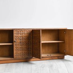 a wooden cabinet sitting on top of a hard wood floor next to a white wall