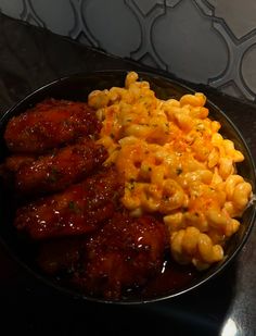 a plate full of macaroni and cheese with chicken wings