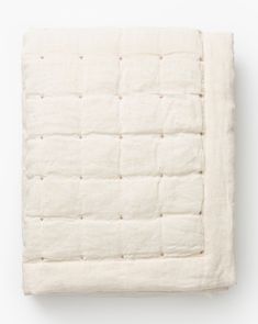 a white quilted blanket on top of a bed