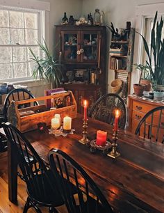 a dining room table with candles on it and other furniture in front of the window