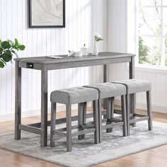 a dining table with four stools and a bench in front of it on a rug